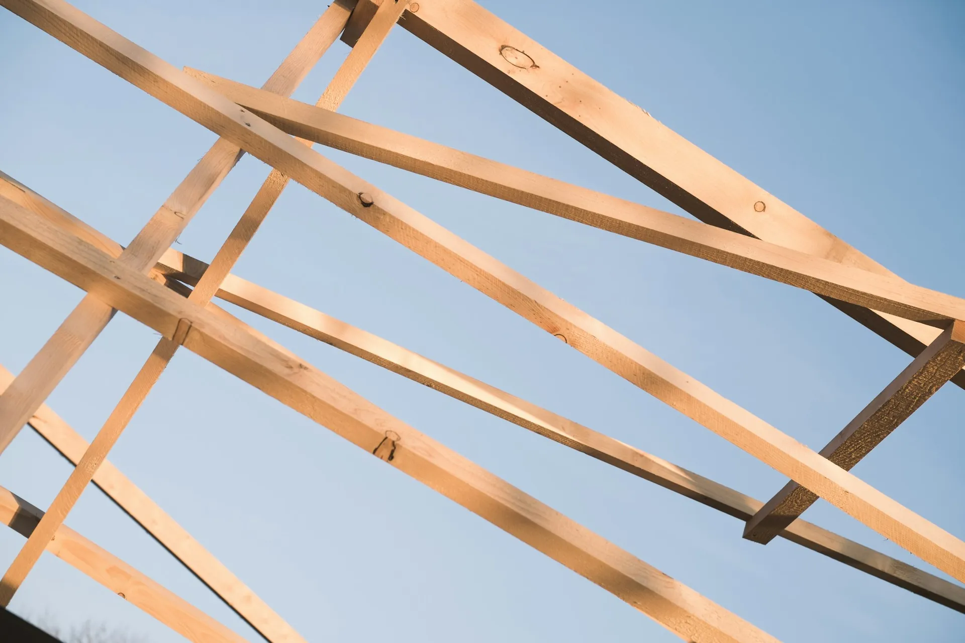 Roof framing of a new home against a clear blue sky